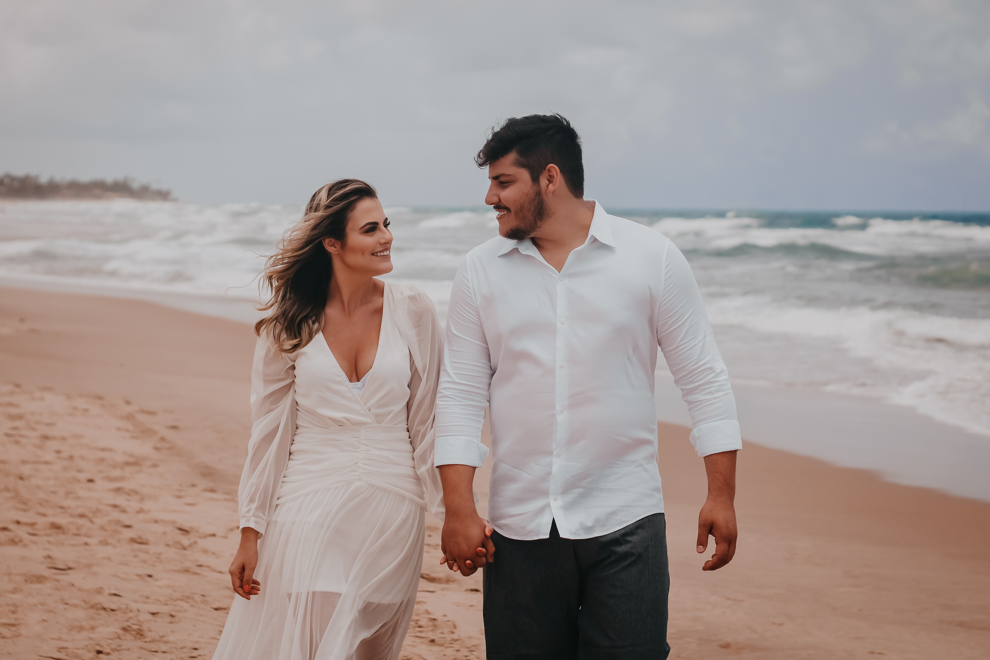 Romantic couple walking on sandy coast of ocean
